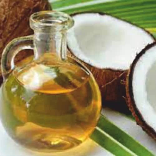 Clear palm-based glycerine in a glass bottle beside palm fruit