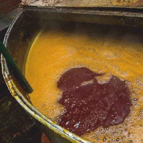 Dark recovered palm sludge oil settling in a processing vessel